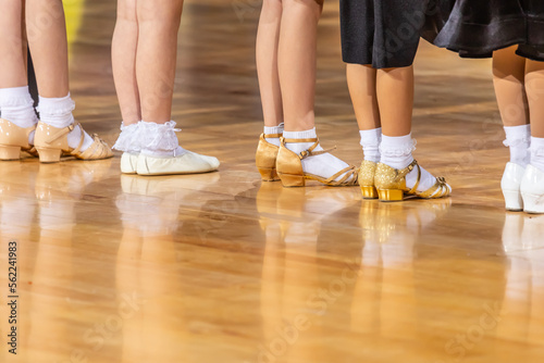 Legs of small girls in ballroom dance shoes.