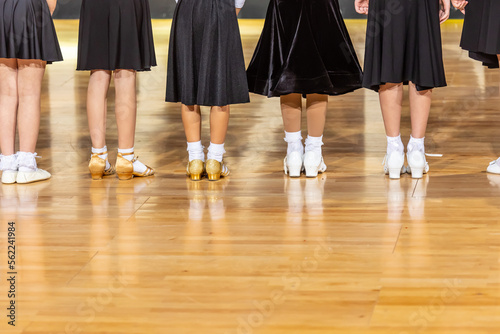 Legs of small girls in ballroom dance shoes.