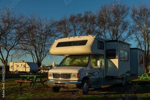 Motorhome and trailer parked at campsite in early morning sunrise