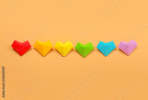 Paper hearts in colors of LGBT flag on beige background. Valentine's Day celebration
