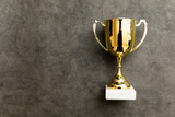 Simply flat lay design winner or champion gold trophy cup on concrete stone grey background. Victory first place of competition. Winning or success concept. Top view copy space