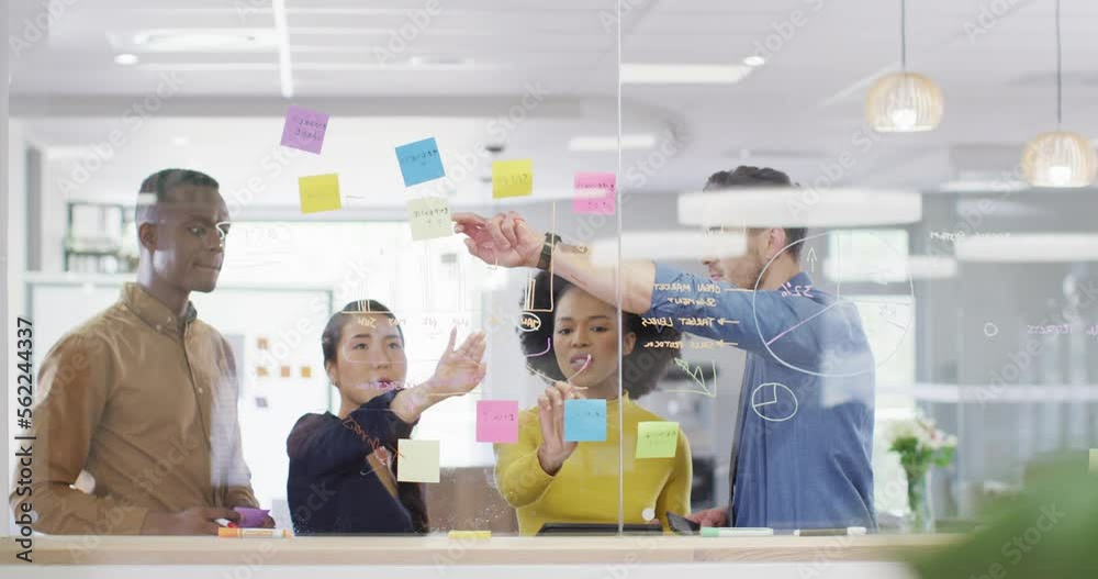 Diverse business people writing on glass blackboard and brainstorming at office, slow motion Diverse business people writing on glass blackboard and brainstorming at office, slow motion