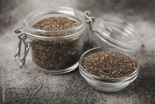 Chia seeds in bowls, spoons and glass jars on a black marble background. SUPERFOOD and antioxidant. Healthy food concept. Gluten free. Copy space.