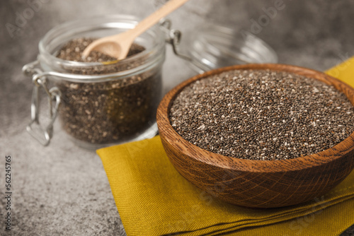 Chia seeds in bowls, spoons and glass jars on a black marble background. SUPERFOOD and antioxidant. Healthy food concept. Gluten free. Copy space.