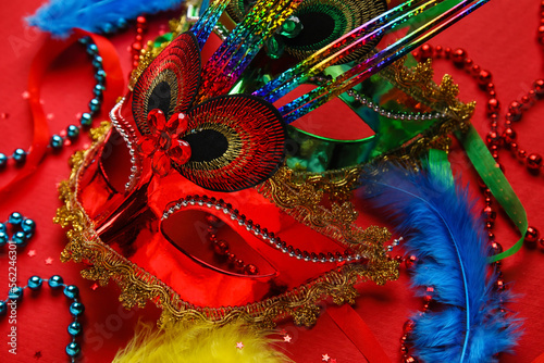Carnival masks for Mardi Gras celebration with feathers and beads on red background, closeup