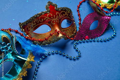 Carnival masks for Mardi Gras celebration with stars and beads on blue background, closeup