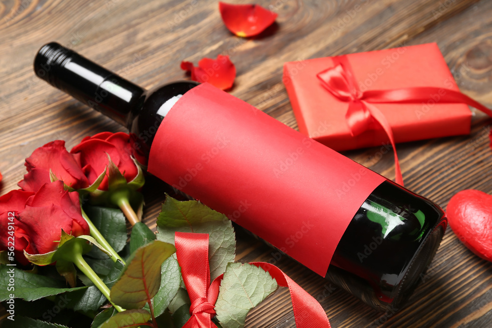 Bottle of wine and rose flowers on wooden table. Valentine's Day