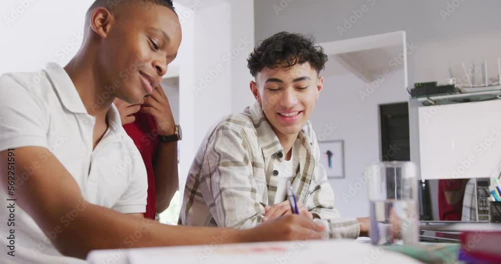 Three happy diverse male teenage friends writing and talking at home, slow motion Three happy diverse male teenage friends writing and talking at home, slow motion