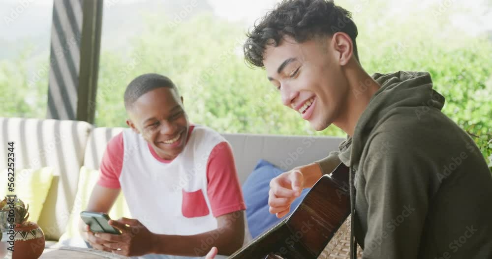 Happy diverse male teenage friends playing guitar at home, slow motion Happy diverse male teenage friends playing guitar at home, slow motion
