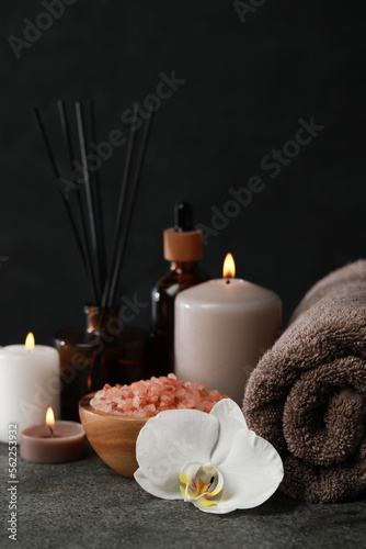 Beautiful composition with burning candles and different spa products on dark grey table