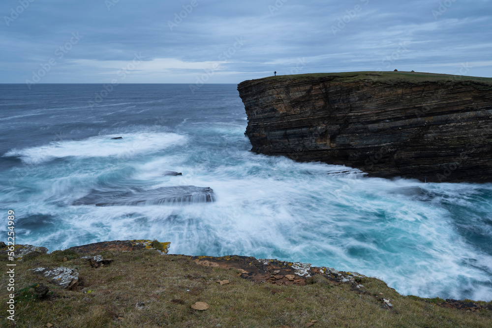 Photographer on cliffs above wild sea at Yesnaby, Orkney, Scotland