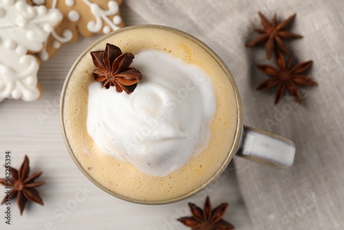 Cup of delicious eggnog with anise star on wooden table, flat lay