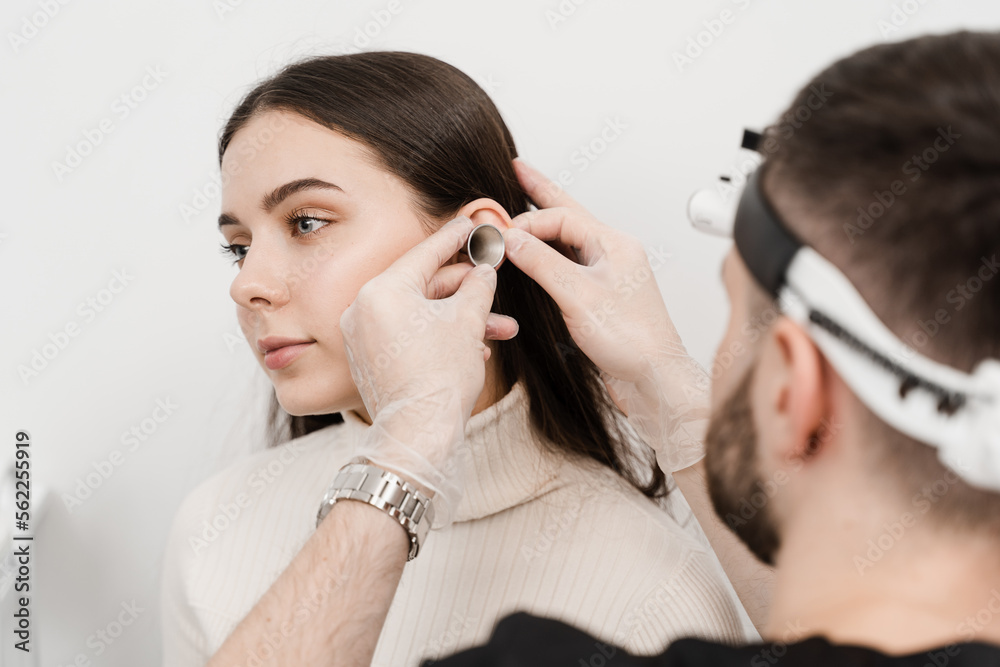 Consultation with otolaryngologist. Treatment of woman ear pain. Otoscopy of ears with ear funnel. ENT doctor with otoscope. Consultation with otolaryngologist. Treatment of woman ear pain. Otoscopy of ears with ear funnel. ENT doctor with otoscope.