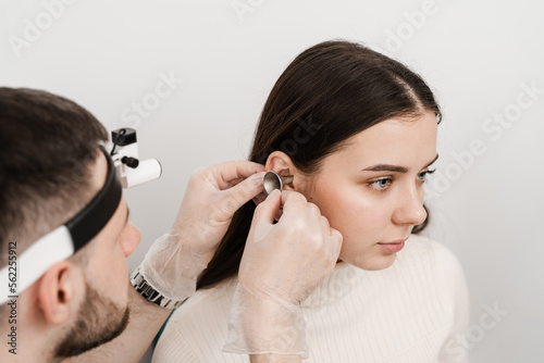 Otoscopy of ears with ear funnel. ENT doctor with otoscope. Consultation with otolaryngologist. Treatment of woman ear pain.