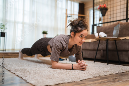 One woman training at home young adult female doing plank exercise