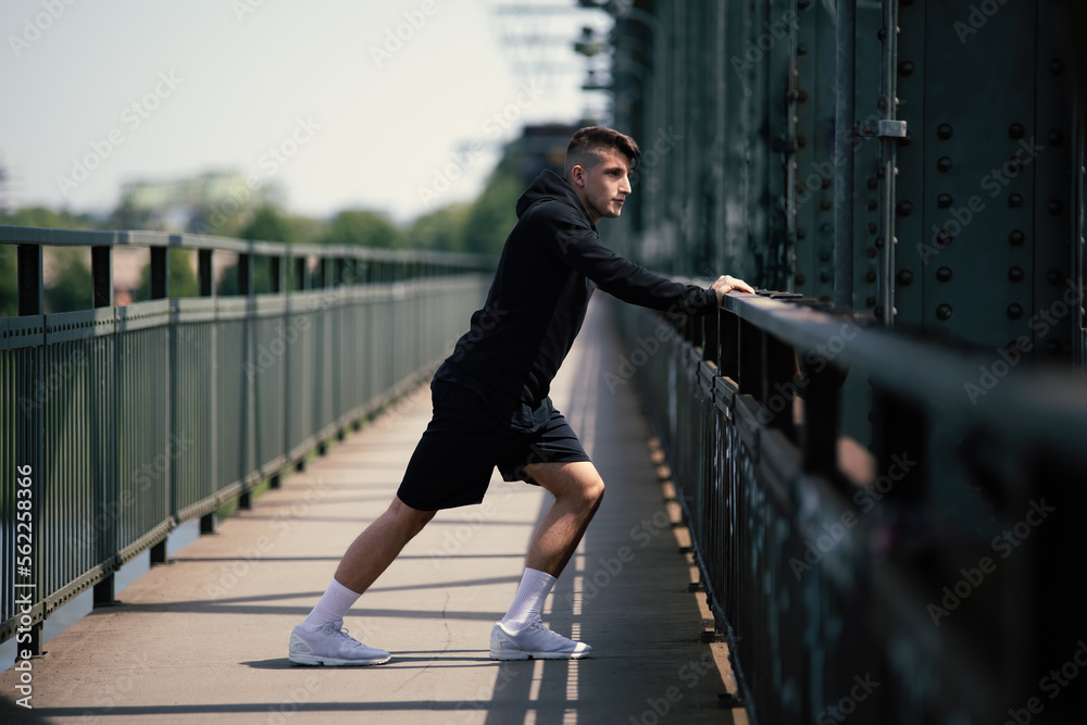 Obraz premium sportive runner stretch tendons and ligaments in legs to warm up the body for perfect recreation to prevent injury