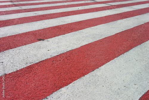Background with red and white stripe. Striped road markings. Pedestrian crossing in city. Flag with diagonal line. Asphalt paint. pavement. Comfortable urban environment. Geometric repeating pattern © brajianni
