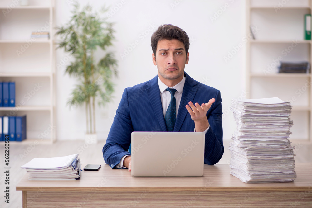 Young male employee and too much work in the office Young male employee and too much work in the office