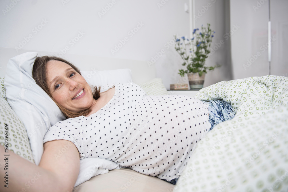 Happy pregnant woman lying in bed, Munich, Bavaria, Germany Happy pregnant woman lying in bed, Munich, Bavaria, Germany