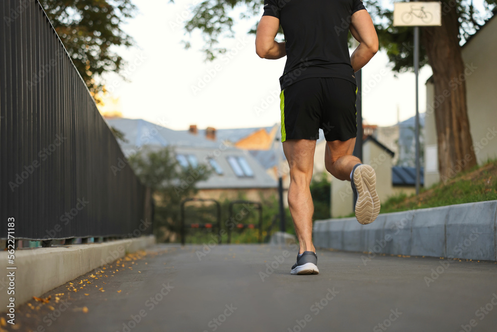 Attractive sporty man in fitness clothes jogging outdoors, closeup