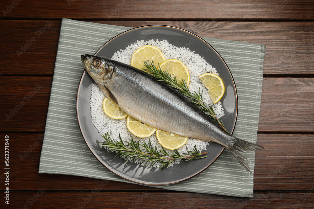 Delicious salted herring, rosemary, salt and lemon on wooden table, top view Delicious salted herring, rosemary, salt and lemon on wooden table, top view