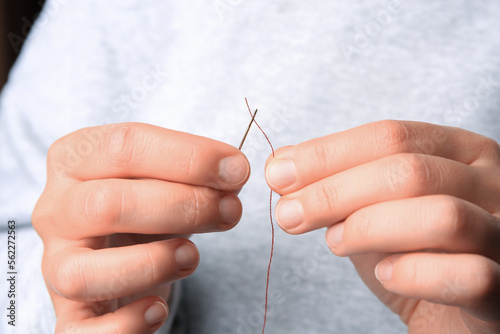 Closeup view of woman threading sewing needle