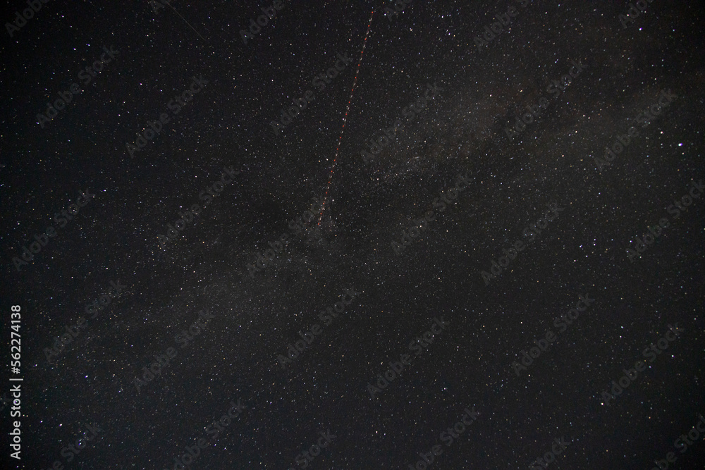 Satellite trail passing through the milky way, night-sky