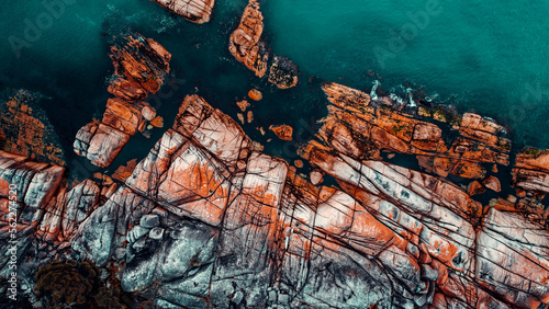 Drone Aerial of Orange Lichen Covered Boulders at Bay of Fires, Tasmania, Green Blue Water, Textured Boulders
