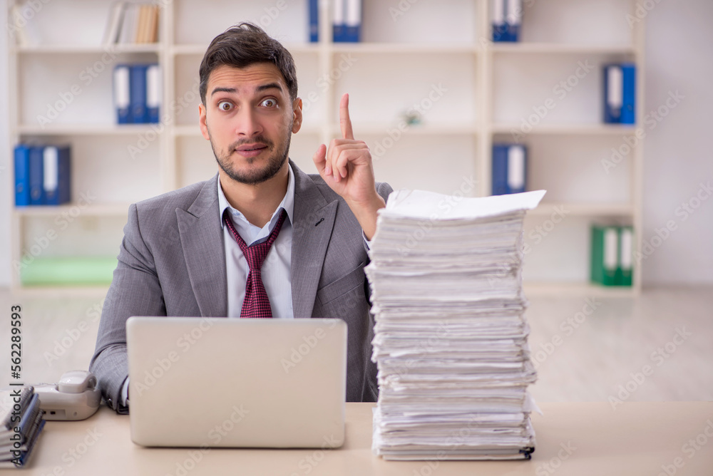 Young male employee unhappy with excessive work in the office Young male employee unhappy with excessive work in the office