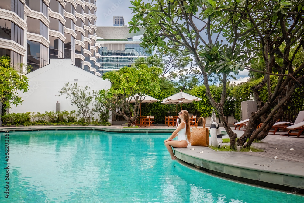 Travel Woman Relaxing on Edge of Luxury City Hotel Swimming Pool