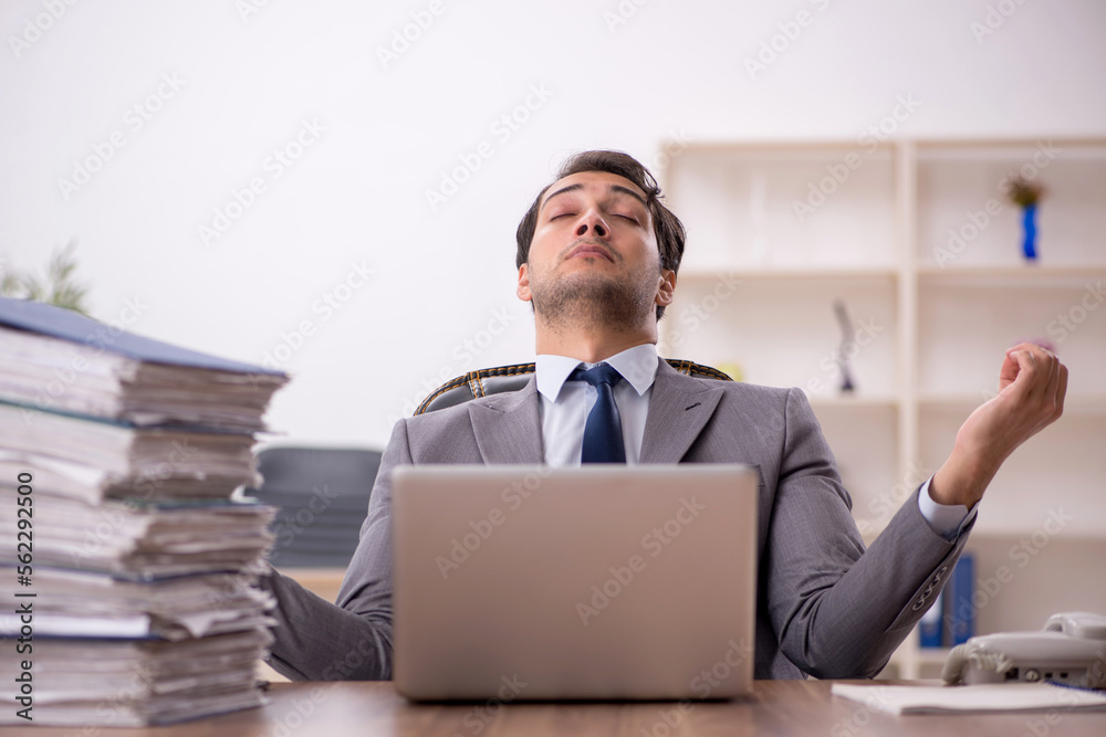 Young male employee and too much work in the office Young male employee and too much work in the office