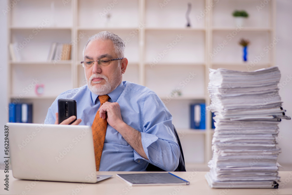 Fototapeta premium Old male employee unhappy with excessive work in the office