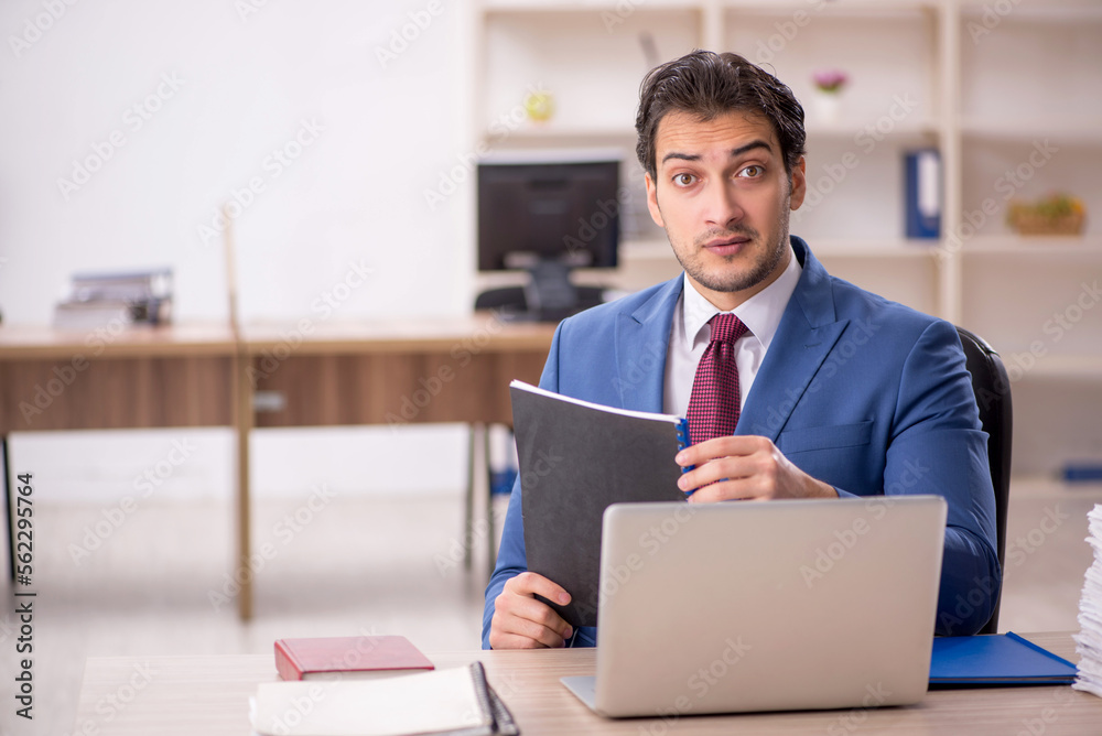 Young male employee and too much work in the office Young male employee and too much work in the office