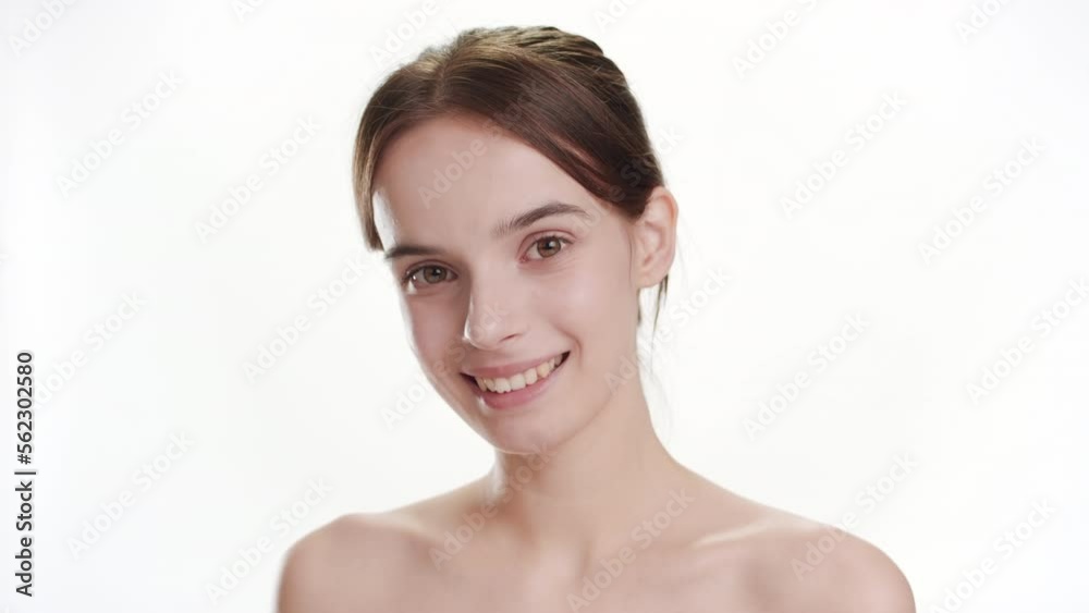Close-up shot of cute young slim Caucasian woman with long brown hair opens her eyes and looks at the camera smiling widely for it on white background | Face care concept Close-up shot of cute young slim Caucasian woman with long brown hair opens her eyes and looks at the camera smiling widely for it on white background | Face care concept