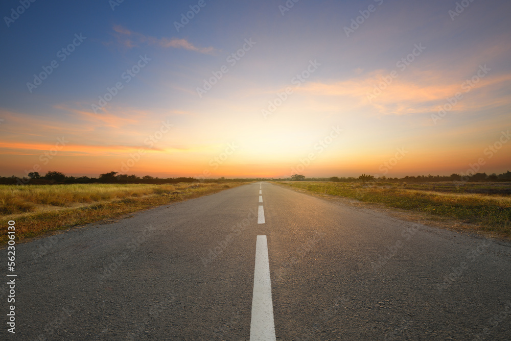 Perspective view of tarmac road in the field with dawn sky background.