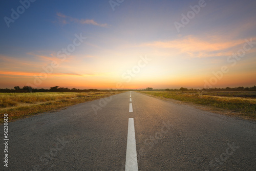 Perspective view of tarmac road in the field with dawn sky background.