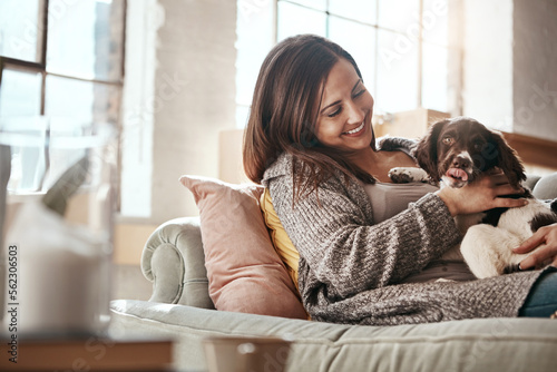 Woman relax on couch, relax and content at home with pet.and happy together with peace and care in living room. Happy woman with puppy, cuddle on sofa and love for animals with smile and happiness