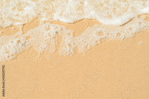 Transparent wave with white foam over the golden sand. Crystal clear sandy beach. Background with eco friendly place for rest.