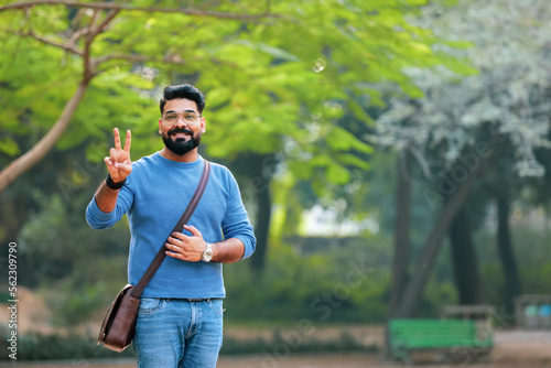 Young indian man showing victory sign at park