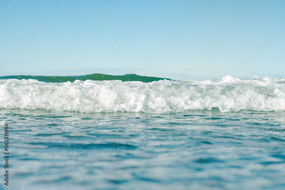 Fototapeta premium Close-up of the sea surface in soft focus. Warm waves of the ocean. Background on the theme of a pleasant romantic holiday. Beach vacation from work.