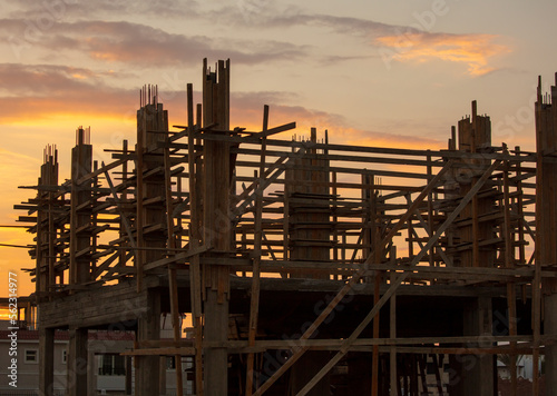 Silhouette of a house under construction at sunset.
