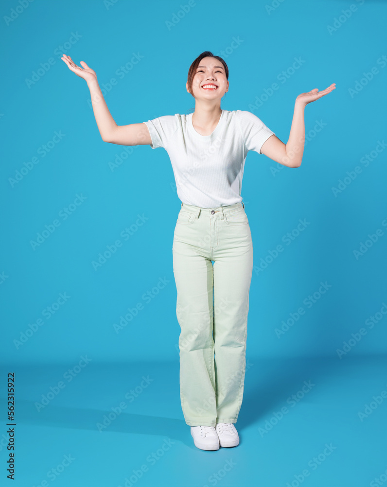 Full length photo of young Asian woman standing on blue backround Full length photo of young Asian woman standing on blue backround
