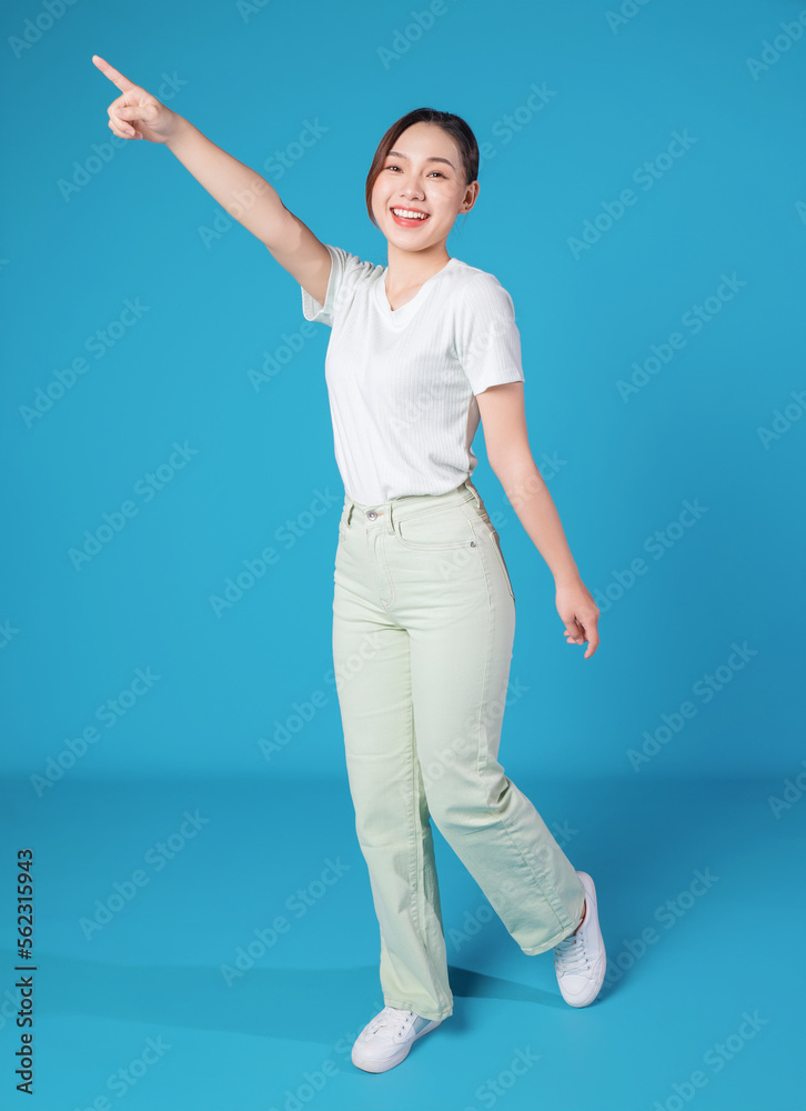 Full length photo of young Asian woman standing on blue backround Full length photo of young Asian woman standing on blue backround