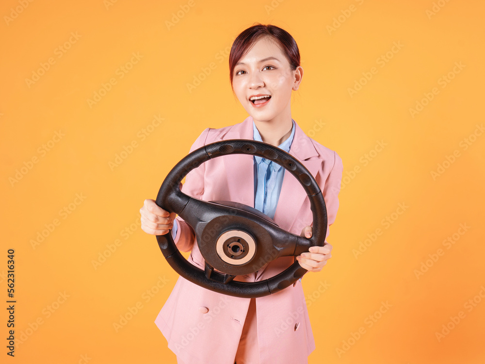 Fototapeta premium Businesswoman holding steering wheel on background