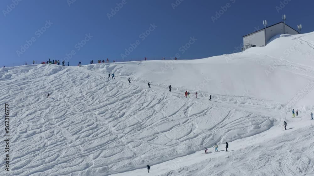 People tourists riding skiing snowboarding on snow slope turn track ski resort outdoor extreme sport activity top shot aerial view. Drone adrenaline alpine speed racing downhill frozen route winter 4k