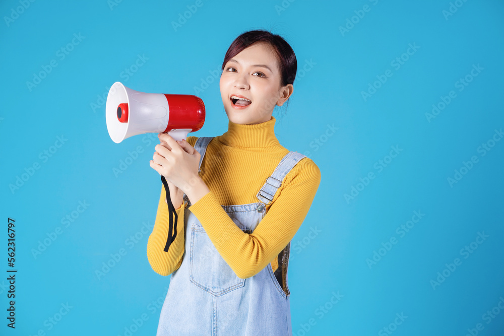 Young Asian girl using megaphone on blue background Young Asian girl using megaphone on blue background