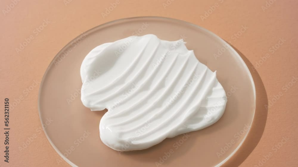 Extreme close-up crane shot of white day cream on watch glass round on beige background | Skin care cream advertisement Extreme close-up crane shot of white day cream on watch glass round on beige background | Skin care cream advertisement