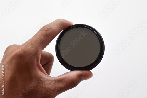 Man's hand holds a ND (neutral density) optical filter isolated on white background