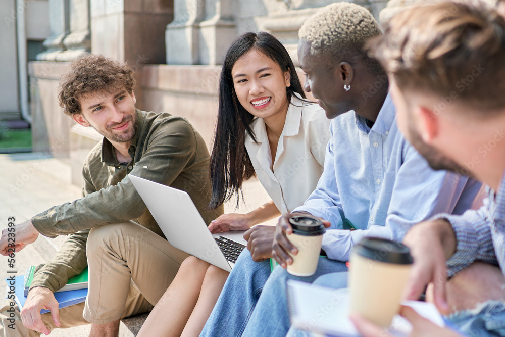 multicultural team of students is chatting on the steps of the campus.
