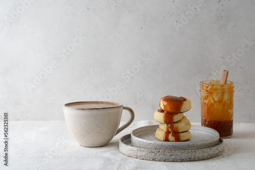 Breakfast minimal wabi sabi and kinfolk style table with cup of coffee, pancakes and caramel sauce